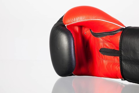 Red and black boxing gloves on a glass table isolated on white background