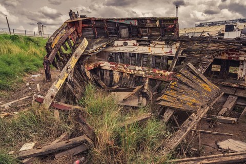 A derelict shipwreck with dark clouds over it, seen in King's Lynn, Norfolk, England, UK