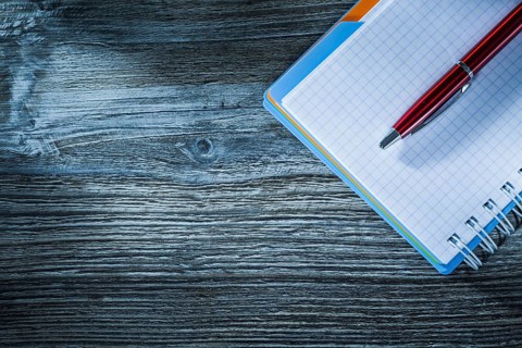 Spiral notebook pen on wooden board