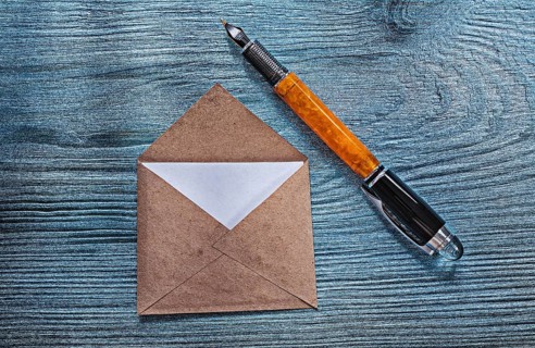 Vintage opened envelope with message fountain pen on wooden board
