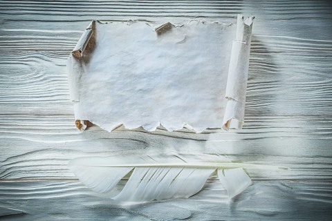 Vintage crumpled paper roll feather on wooden board