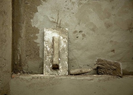 Dirty grunge cement trowel hand tools on fresh mortar wall