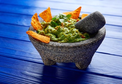 Guacamole with nachos avocado in Mexican molcajete on blue wood table