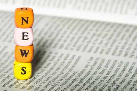 Word news.Wooden cubes on newspaper. Close up studio shot