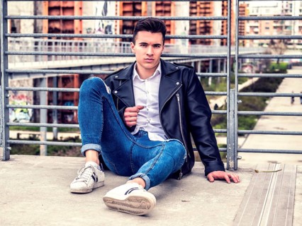 One handsome young man in urban setting in European city, sitting, wearing black leather jacket and