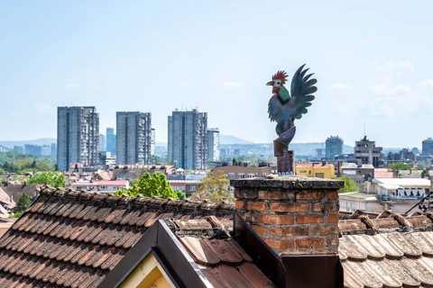 Weathercock on chimney above old town roofs