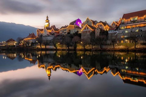 Christmas illuminated house facade of Frohnleiten reflected in the river Mur, Frohnleiten, Styria,