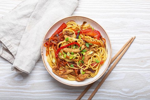 White bowl with Chow Mein or Lo Mein, traditional Chinese stir fry noodles with meat and
