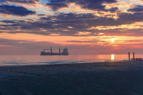 Sunset at the Seaside with a large ship and beautiful light and light reflections on the water