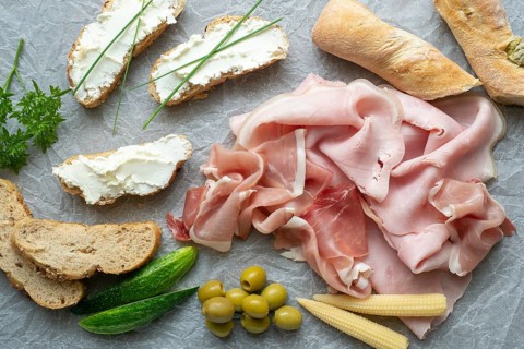 Cold appetizer. Cold cuts. Different snacks on a white crumpled paper, ham, bread, vegetables, from