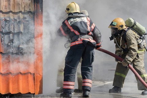 Firefighters extinguishing fire from fire hose, using firefighting water-foam barrel with