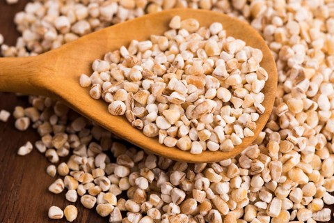 Barley groats on wooden spoon