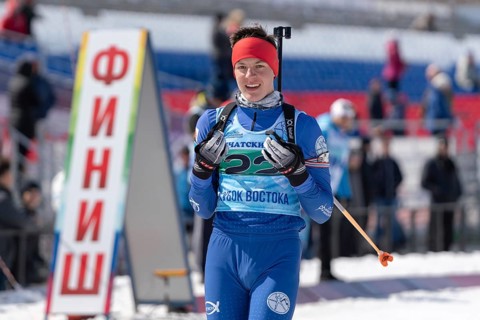 Portrait of sportsman biathlete Sporshev Nikita at finish line after skiing and rifle shooting.