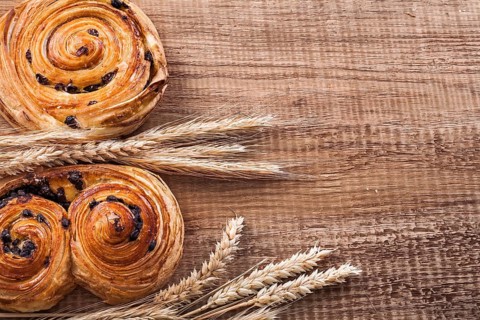 Golden wheat ears fresh-baked buns with raisins on oaken wooden board food and drink concept