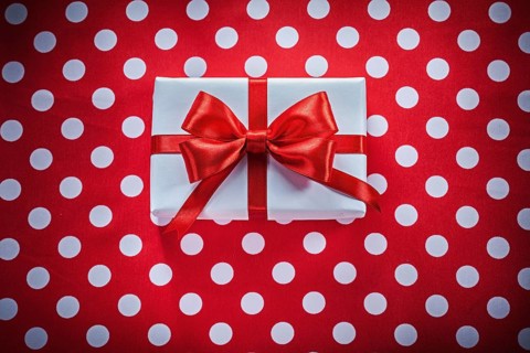White gift box with knot on polka-dot red fabric holidays concept