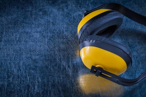 Noise reduction protective earmuffs on scratched metallic surface construction concept