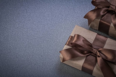 Giftboxes in brown wrapping paper on grey background celebrations concept