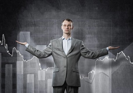 Businessman with spread arms and growing graphs on chalkboard