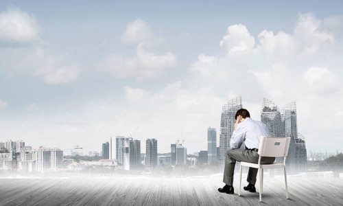 Businessman sitting on an office chair with his back, thinking and holding his head