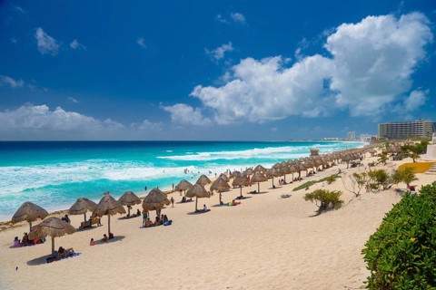 Umbrellas on a sandy beach with azure blue water on a sunny day near Cancun, Mexico, Central
