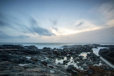 Beach, with lava rocks and vegetation, view of the sea in the evening at sunset. Landscape with