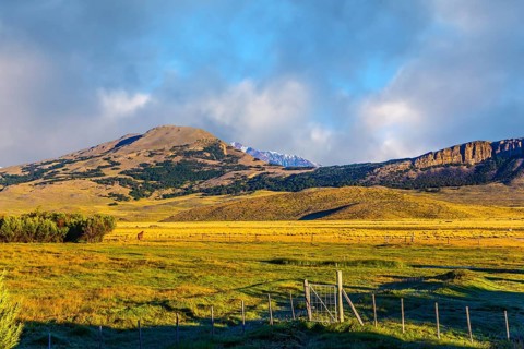 The huge possessions of a private hacienda are surrounded by distant mountains. The grass field is