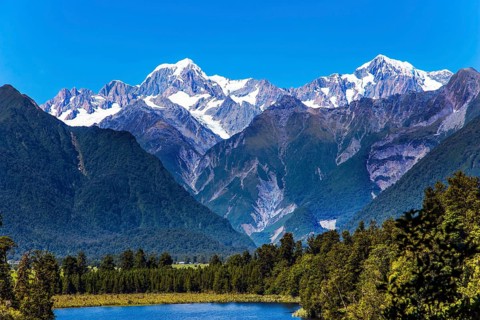 Mountain peaks covered with snow. Mirror glacial Lake Matheson surrounded by mountains Mount Cook
