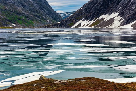 Kingdom of the Snow Queen. Lake Djupvatnet is covered with ice in July. The mountains are covered