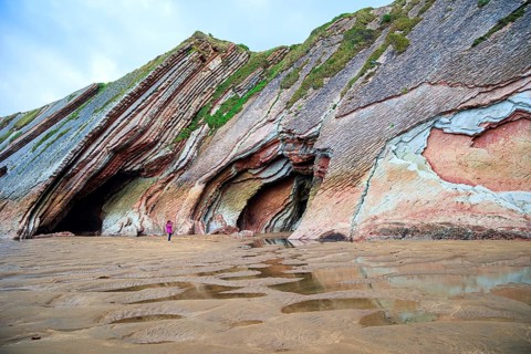Picturesque cave on the beach. Flysch - underwater rocks exposed at low tide. Low tide in the