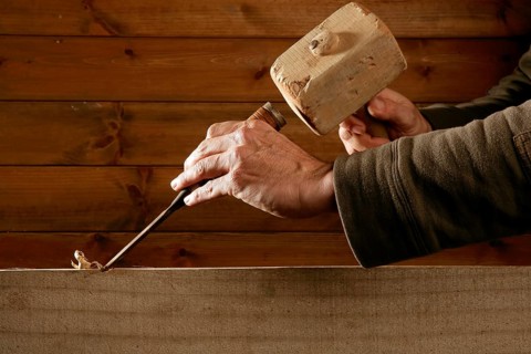 Gouge wood chisel carpenter tool hammer in hand working wooden background