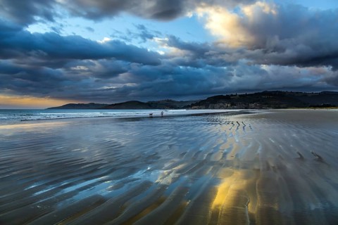 Sunrise over the ocean. Low tide. Strips of sand and water left by the ocean tide. New Zealand,