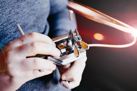 Hands using a mechanical tool with copper wire, emphasizing precision