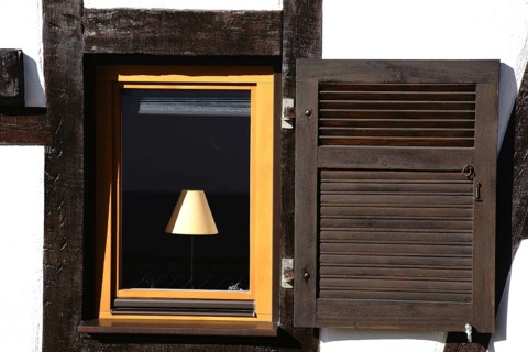 The nostalgic window of a half-timbered house with a lamp behind the window pane