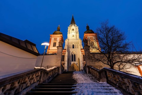 Snow on staircase, facade of the pilgrimage church, basilica of Mariazell, blue hour in the early