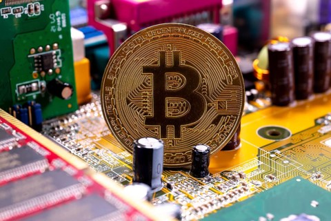 Virtual cryptocurrency money Bitcoin golden coin on a computer printed circuit board PCB. The