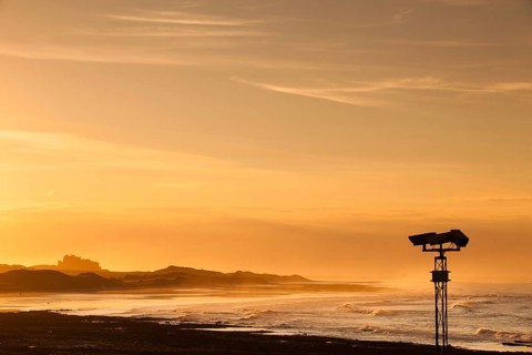View of the Bamburgh castle in a spectacular sunset from the Seahouses, Great Britain