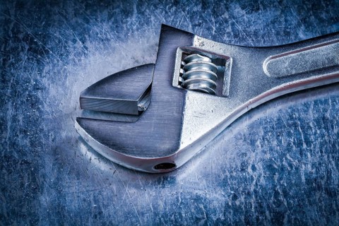 Metal adjustable spanner on scratched metallic background construction concept