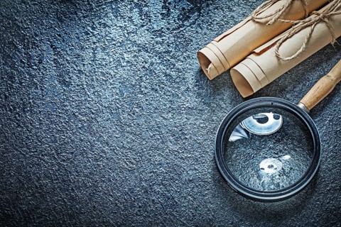 Vintage paper rolls magnifying glass on black surface