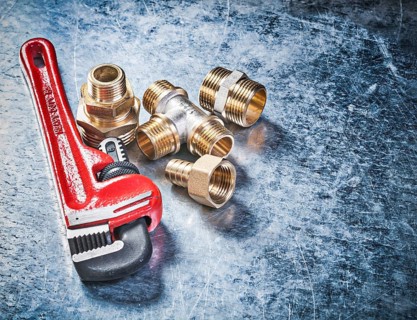Pipe wrench brass hose nipples on scratched metallic background plumbing concept