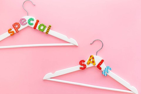 Creative top view flat lay white hangers special sale text pastel pink background copy space