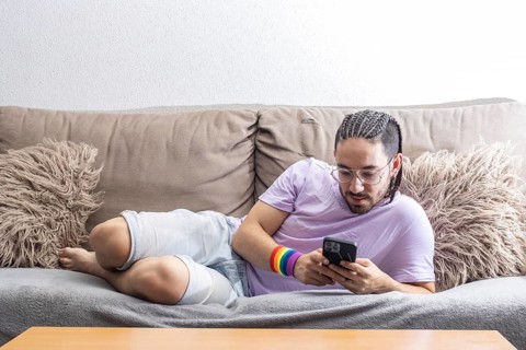 Portrait of gay man lying on sofa with mobile phone
