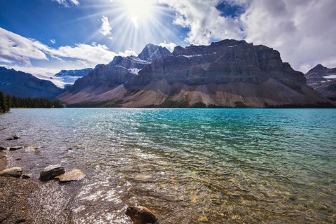 The cold waters of the lake surrounded by scenic Canadian Rocky Mountains. Azure Bow Lake in Banff