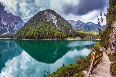Magnificent Alpine lake Lago di Braies. Walking trail around the lake is fenced with wooden
