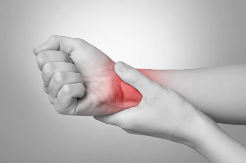 A young woman holding her painful wrist
