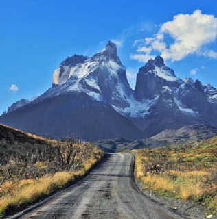 Dreamland Patagonia. Snow-covered cliffs of Los Cuernos, to them is a road of black gravel