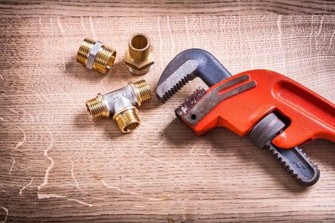 Plumbing Tools Composition Of Brass Pipe Connectors On Wooden Board and Monkey Wrench