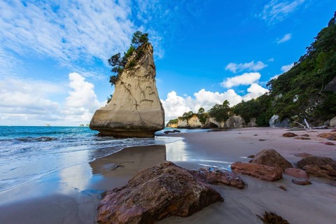 The North Island of New Zealand. Ocean low tide in Cathedral Cove at sunset. Huge boulders and