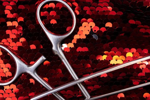 Detailed view of surgical instruments on shimmering red sequins