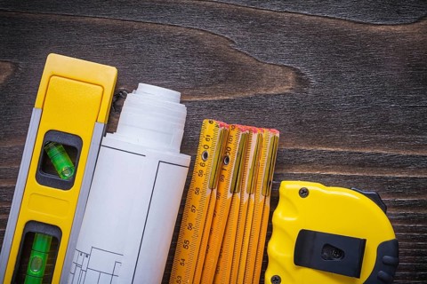Roll of blueprints construction level tape-line and wooden meter on vintage wood board maintenance