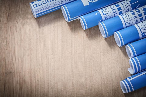 Pile of blue rolled up construction drawings on wooden board